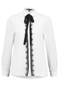 Camicia bianca con maniche lunghe, bordatura in pizzo nero lungo la parte frontale e un fiocco nero. Presenta un colletto classico e una texture del tessuto liscia e morbida.