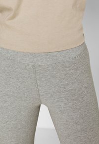 Leggings de color gris claro, hechos de una tela suave y elástica; cuentan con una cintura sin costuras y una textura suave en toda su superficie.