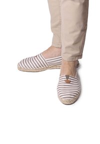 Scarpe slip-on in tessuto a righe beige e grigio con suola in corda di juta e un piccolo accento marrone vicino all'apertura.