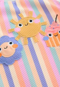 Bunt bedruckter Stoff mit gestreiften Mustern in Pastellfarben. Enthält bestickte Figuren von Sonne, Wolke und Cupcake mit Gesichtszügen.