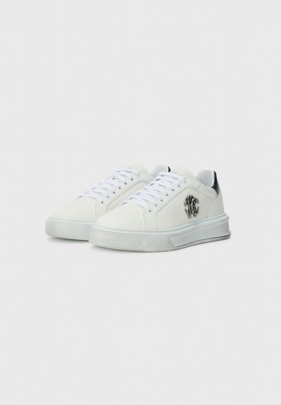 Sneaker in pelle bianca con finitura liscia, dotate di una suola spessa, allacciatura frontale e un accento nero sul tallone. Decorate con un logo.