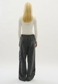 Schwarze Cargo-Hosen mit entspannter Passform, ausgestattet mit elastischem Bund, seitlichen Taschen und einem gestickten 'L5'-Detail auf der Rückseite.