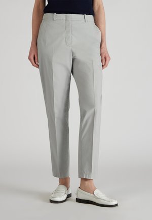 Pantalones tapered de color gris claro hechos de una tela suave; cuentan con bolsillos laterales, pasadores para cinturón y un cierre con cremallera, combinados con mocasines blancos.