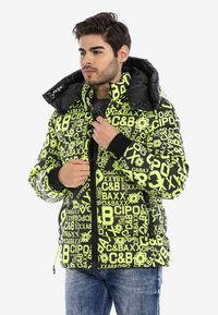 Puffjacke mit einem auffälligen schwarzen und neongrünen grafischen Muster, ausgestattet mit einem hohen Kragen, einem Reißverschluss und gerippten Bündchen. Weicher Stoff.