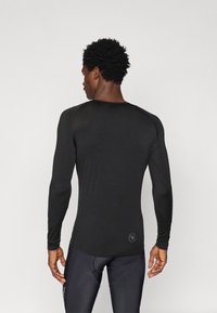 Czarna, długosleeve'owa koszulka sportowa z okrągłym dekoltem, Slim fit oraz gładką fakturą, z małym logo w pobliżu dolnego wcięcia.