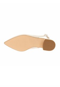 Zapato de tacón alto de punta en piel color crema con un tacón delgado, que presenta un detalle de hebilla redonda y una suela beige suave.