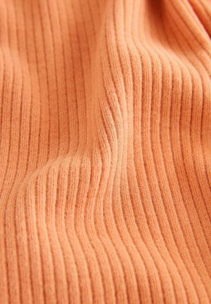 Soft ribbed fabric with vertical knit lines in a warm orange tone, showing gentle folds and texture variations.