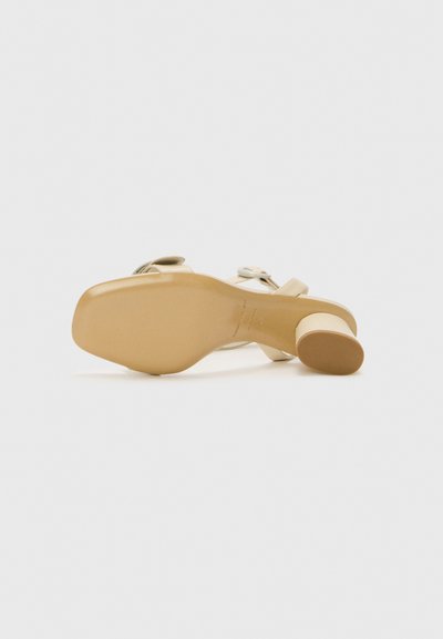 Beige højhælede sandal med en glat læderoverdel, en rund tå og en smart, buet hæl. Sålen er i en lys tan-farve.