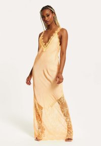 Sleeveless, deep V-neck dress features a satin orange body with intricate lace trim and lace overlay at the hem, creating a layered effect.