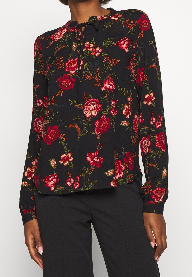 Schwarze Bluse mit Blumenmuster und langen Ärmeln, verziert mit roten und rosa Blumen, mit einer Schleifen-Nackenpartie und entspannter Passform. Weicher Stoff mit glatter Textur.
