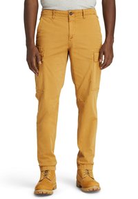 Cargo-byxor i senapsgul, tillverkade av bomull, med sidofickor, rak ben-design och en slät textur. I kombination med bruna kängor.