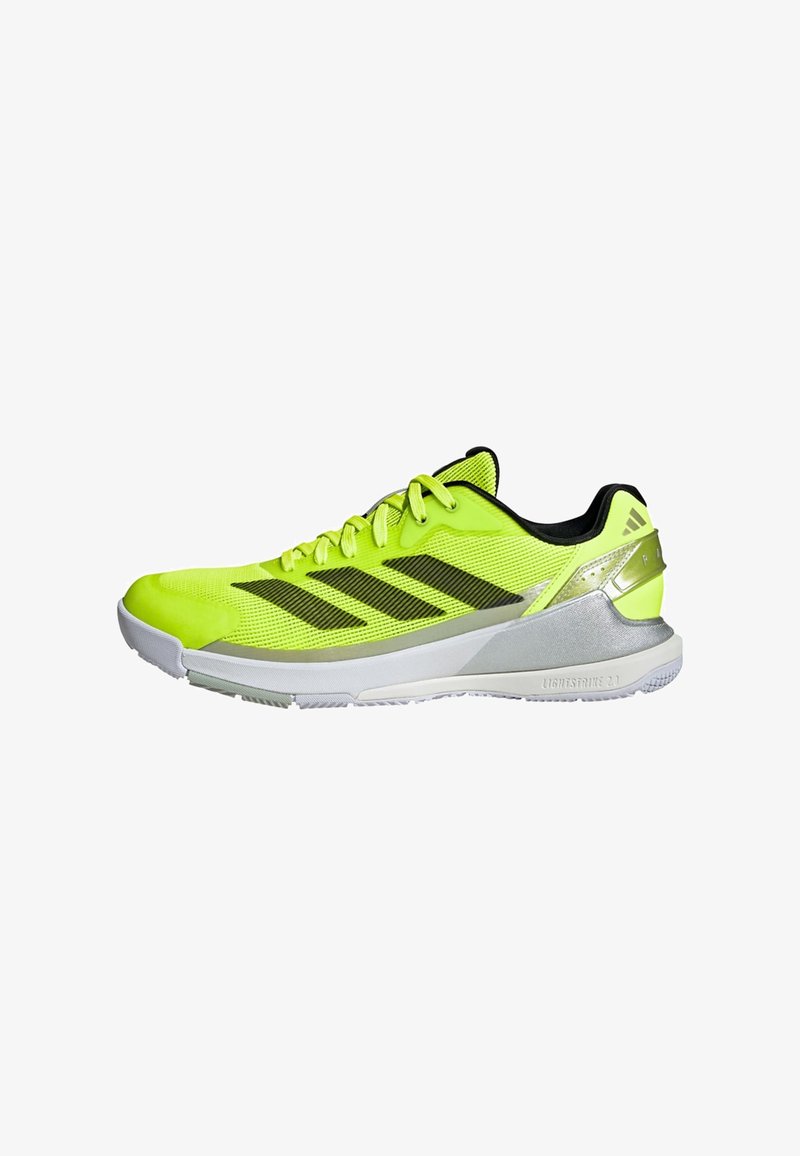 Chaussure de sport Adidas jaune néon et noire avec dessus en mesh, semelle intermédiaire blanche, renfort de talon argenté et trois bandes noires sur le côté.