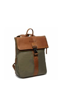 Sac à dos en toile et cuir de couleur vert olive et marron, avec une fermeture à rabat, une boucle et une poche zippée sur le côté. Texture lisse, design structuré.