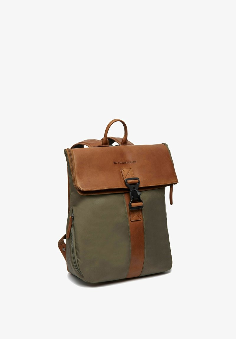 Sac à dos en toile et cuir de couleur vert olive et marron, avec une fermeture à rabat, une boucle et une poche zippée sur le côté. Texture lisse, design structuré.