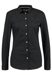 Černá košile s dlouhým rukávem a límečkem na knoflíky, bílé knoflíky a malé logo na hrudi. Hladká látka, přiléhavý střih.