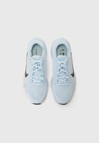Helle blaue Nike-Laufschuhe mit strukturiertem Obermaterial und schwarzem Swoosh, von oben betrachtet. Die Schnürsenkel sind gebunden, was das schlanke Design zur Geltung bringt.