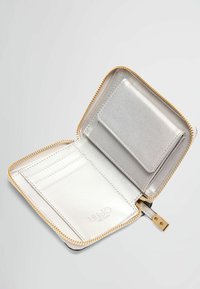 Portafoglio metallico argento con chiusura a zip. L'interno presenta slot per carte e un compartimento piatto, rifinito con dettagli in hardware dorato.