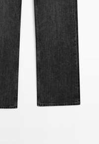 Jeans in denim grigio scuro con gamba dritta, distesi su una superficie bianca mostrando l'orlo inferiore e le cuciture delle gambe.