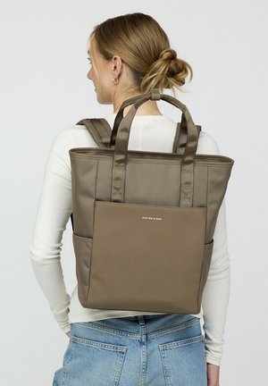 Braune Stofftasche mit doppelten Griffen und Schulterriemen. Vordertasche und Logo sichtbar. Glatte Textur, rechteckige Form, minimalistisches Design.