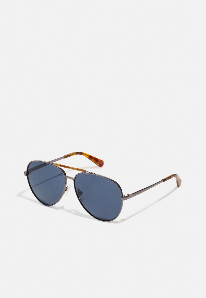 Okulary aviator z ciemnoniebieskimi szkłami, metalicznie szarym ramieniem i świątecznymi zausznikami w stylu żółwia. Minimalistyczny design z przezroczystymi noskami.
