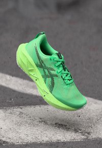 Grüner Laufschuh mit einem Mesh-Obermaterial, strukturierten Details und einer dicken Sohle. Enthält schwarze Markenlogos und Schnürsenkel und ist für Leistung ausgelegt.