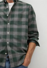 Grünes und graues karriertes Hemd aus Flanellmaterial, mit einem Button-Down-Kragen, einer einzelnen Brusttasche und hochgekrempelten Ärmeln.