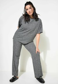 Ensemble à deux pièces gris à côtes comprenant un haut ample à manches courtes et un pantalon large, complété par des chaussures noires à enfiler.