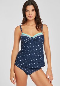 Top de baño de lunares marinos con acentos en azul claro, que cuenta con tirantes ajustables, detalle de frente retorcido y parte inferior de color sólido a juego.