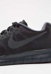 Le sneaker Nike Free nere presentano una parte superiore in mesh traspirante, un design snello, una punta rotonda e una suola nera testurizzata con dettagli grigi.