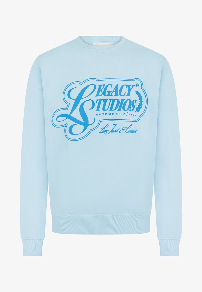 Light blue sweatshirt with long sleeves and ribbed cuffs, featuring large blue "Legacy Studios Automobile, Inc." text and decorative design on front.