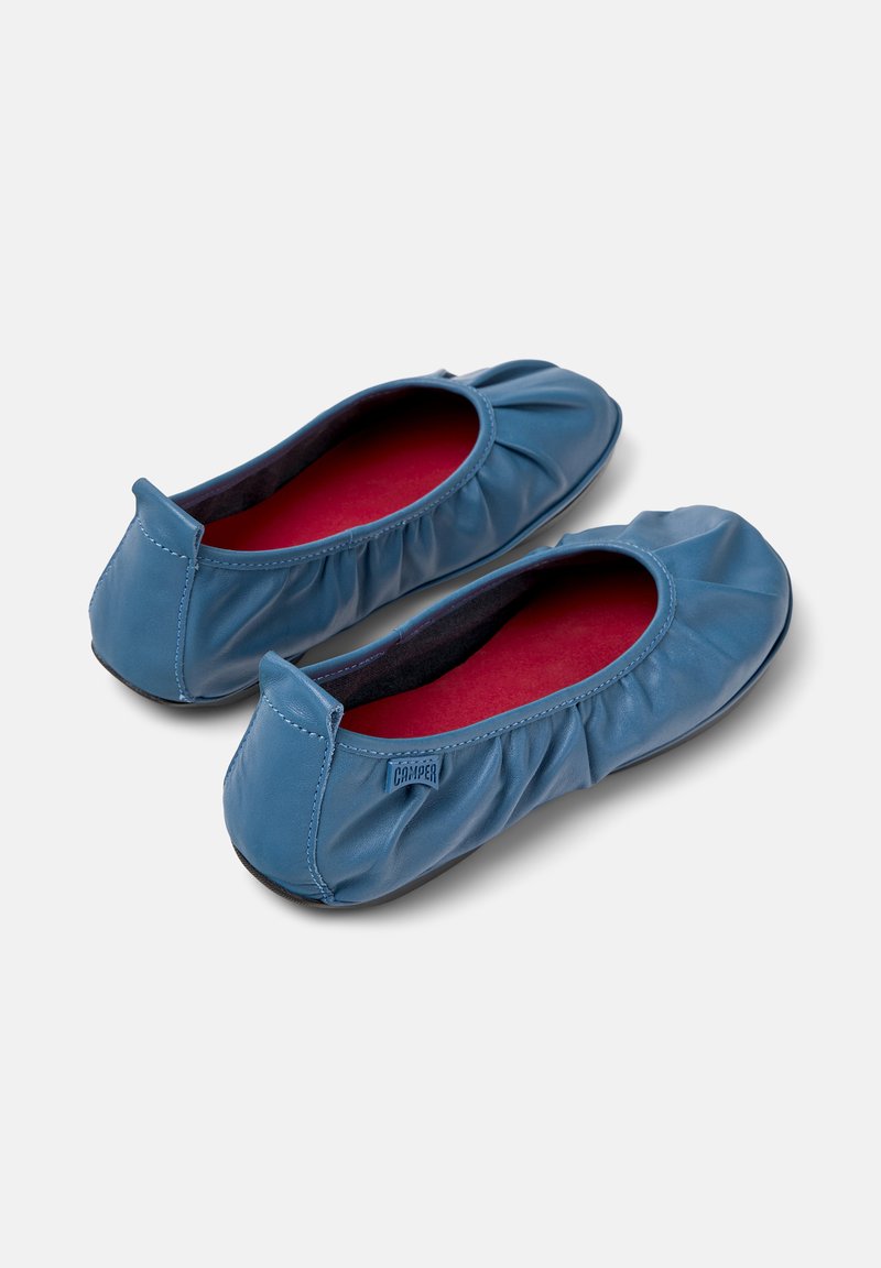 Ett par blå läderballetskor med röda innersulor och rynkade detaljer, placerade sida vid sida på en vit bakgrund.