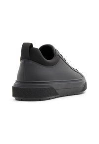 Zapatilla negra con un acabado suave y mate, que cuenta con un cuello acolchado, suela texturizada y cordones resistentes para un ajuste seguro.