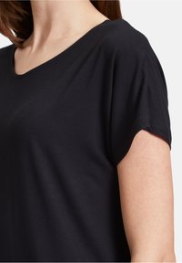 Top nero a maniche corte con scollo ampio, realizzato in morbido tessuto di cotone. Presenta una vestibilità comoda e una texture liscia.