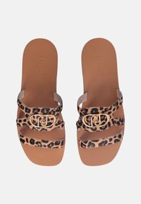 I sandali con stampa leopardata presentano fasce larghe con un accento in oro e una soletta marrone. Il materiale ha una texture liscia e un design piatto.