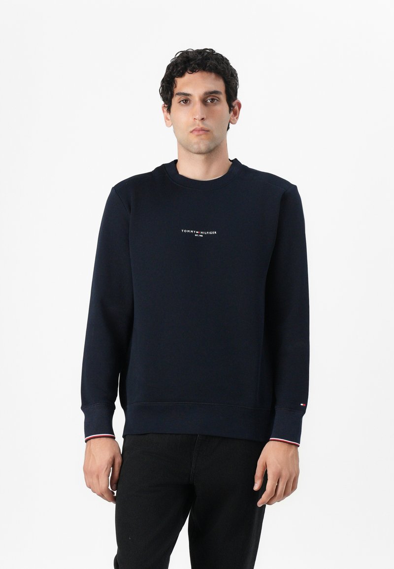 Sweatshirt azul-marinho feito de algodão, apresentando um decote redondo, punhos canelados e um pequeno logotipo no peito. Textura suave sem padrões.