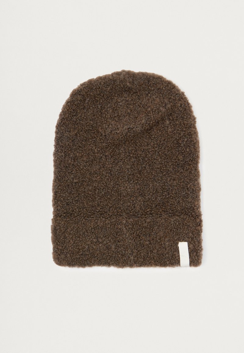 Béret en tricot marron, texture douce, sommet effilé et bord replié ; présente une petite étiquette blanche sur le côté.