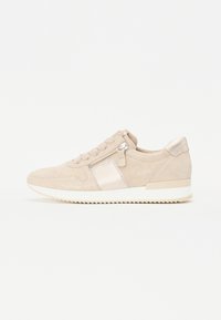 Baskets en daim beige avec un panneau métallique lisse, une fermeture éclair latérale et des lacets ton sur ton. La semelle est blanche avec un motif texturé pour une meilleure traction.