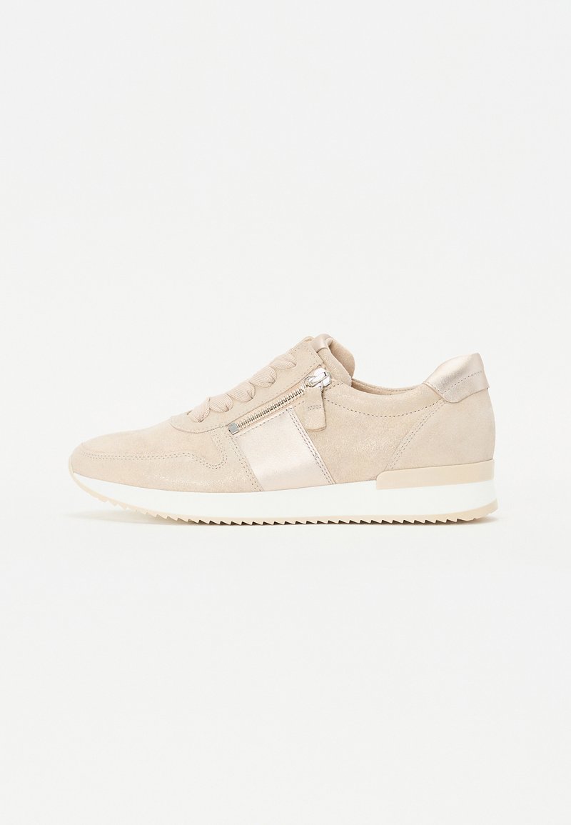 Beige suede sneaker featuring a smooth metallic panel, a side zipper, and tonal laces. The sole is white with a textured pattern for traction.