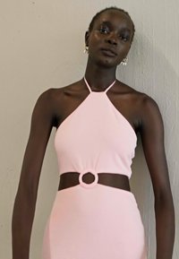 Sundress rosa de halter com um corte circular na cintura. O tecido parece suave e ajustado, destacando uma silhueta elegante.