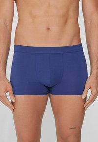 Modré boxerky vyrobené z měkké tkaniny s hladkým povrchem. Mají přiléhavý střih a široký elastický pas. Žádné viditelné vzory ani akcenty.