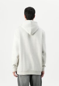 Lys grå hettegenser med kengurulomme og snor i hetten. Har ribbede mansjetter og hem, laget av myk, børstet fleece.