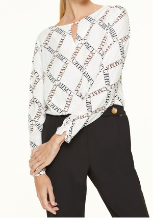 Langsleeve blouse in witte stof met een herhalend patroon van zwarte en bruine tekst. Sleutelgatdetail bij de halslijn, met knoopmanchetten.