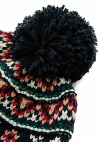 Bonnet tricoté avec un pompon bleu marine, un motif multicolore complexe avec du rouge, du vert, du crème et du noir, et une texture en laine épaisse.