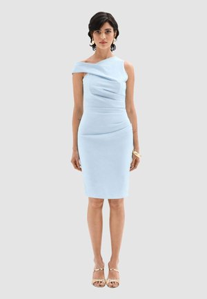 Donna che indossa un abito azzurro chiaro monospalla al ginocchio con dettagli arricciati, orecchini dorati, braccialetto e tacchi aperti dorati.