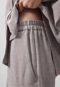 Lichtgrijze co-ord set met een losvallende, gestructureerde blazer en broek met elastische tailleband, zachte plooien en zijzakken.