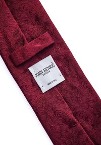 Burgunderfärgad mönstrad slips med en texturerad yta, som har en etikett med texten "JOHN HENRIC, Sverige, Tillverkad i Italien."