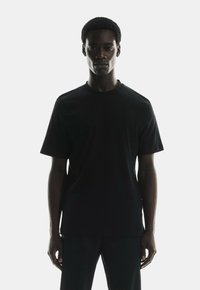 Black cotton crew-neck t-shirt, short sleeves, regular fit, smooth texture, minimalistic design, no visible branding.
