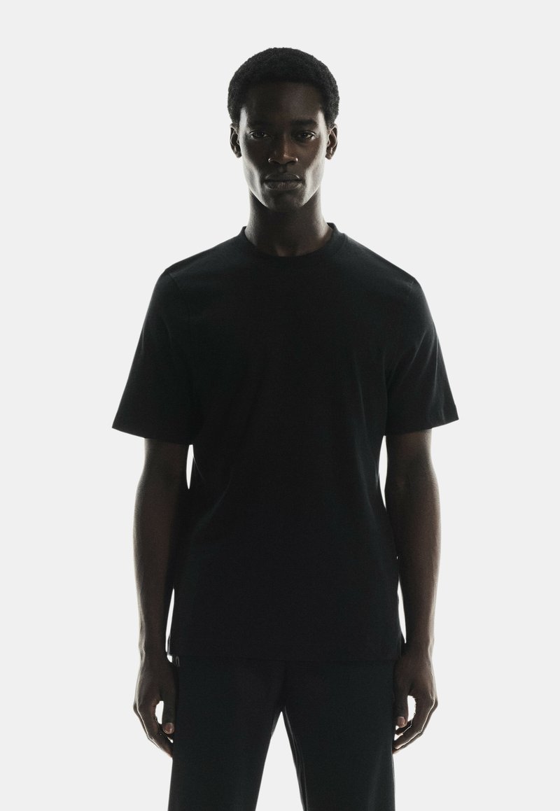 Black cotton crew-neck t-shirt, short sleeves, regular fit, smooth texture, minimalistic design, no visible branding.
