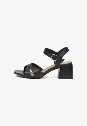 Sandale en cuir noir à bout ouvert avec brides croisées à l'avant, bride de cheville réglable avec boucle argentée et petit talon bloc.