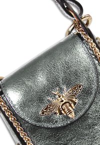 Metallische groene leren handtas met een gouden bij-embleem, kettingriem en een gestructureerd oppervlak met een ronde klepsluiting.